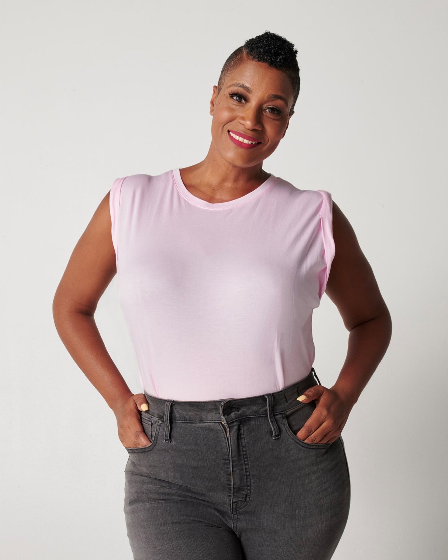 Pink pima cotton muscle tee on smiling black model wearing black jeans with hands in pockets