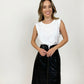 Thin, white model with brunette hair smiling while wearing white pima cotton muscle tee and long black leather skirt holding her hands in front