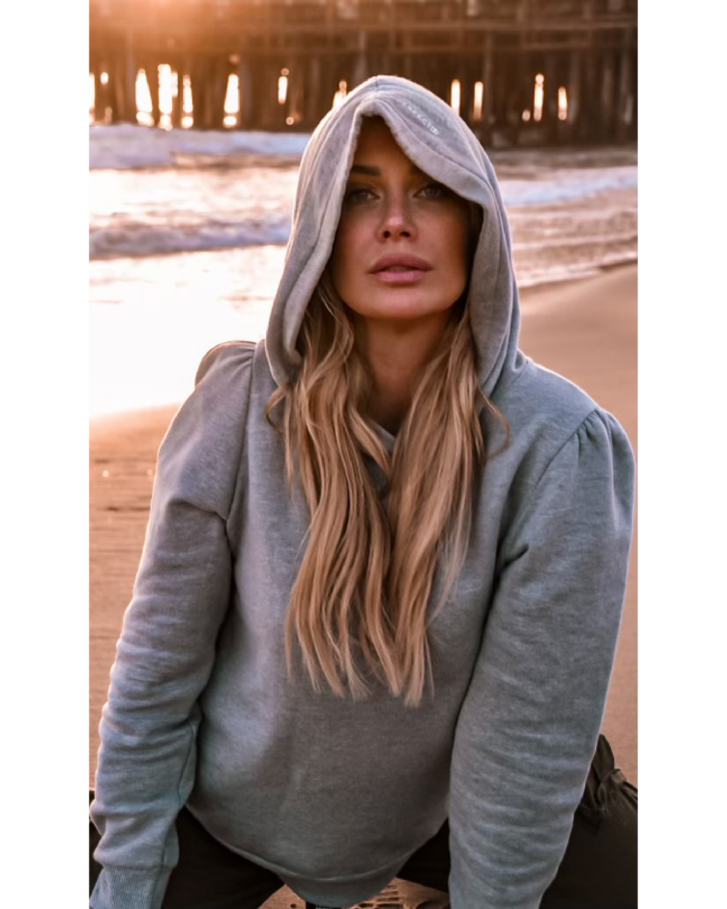 Heather grey cotton fleece long sleeve sweatshirt on model kneeling on beach at sunset