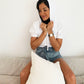 White cotton short sleeve sweatshirt on model sitting on couch holding hood