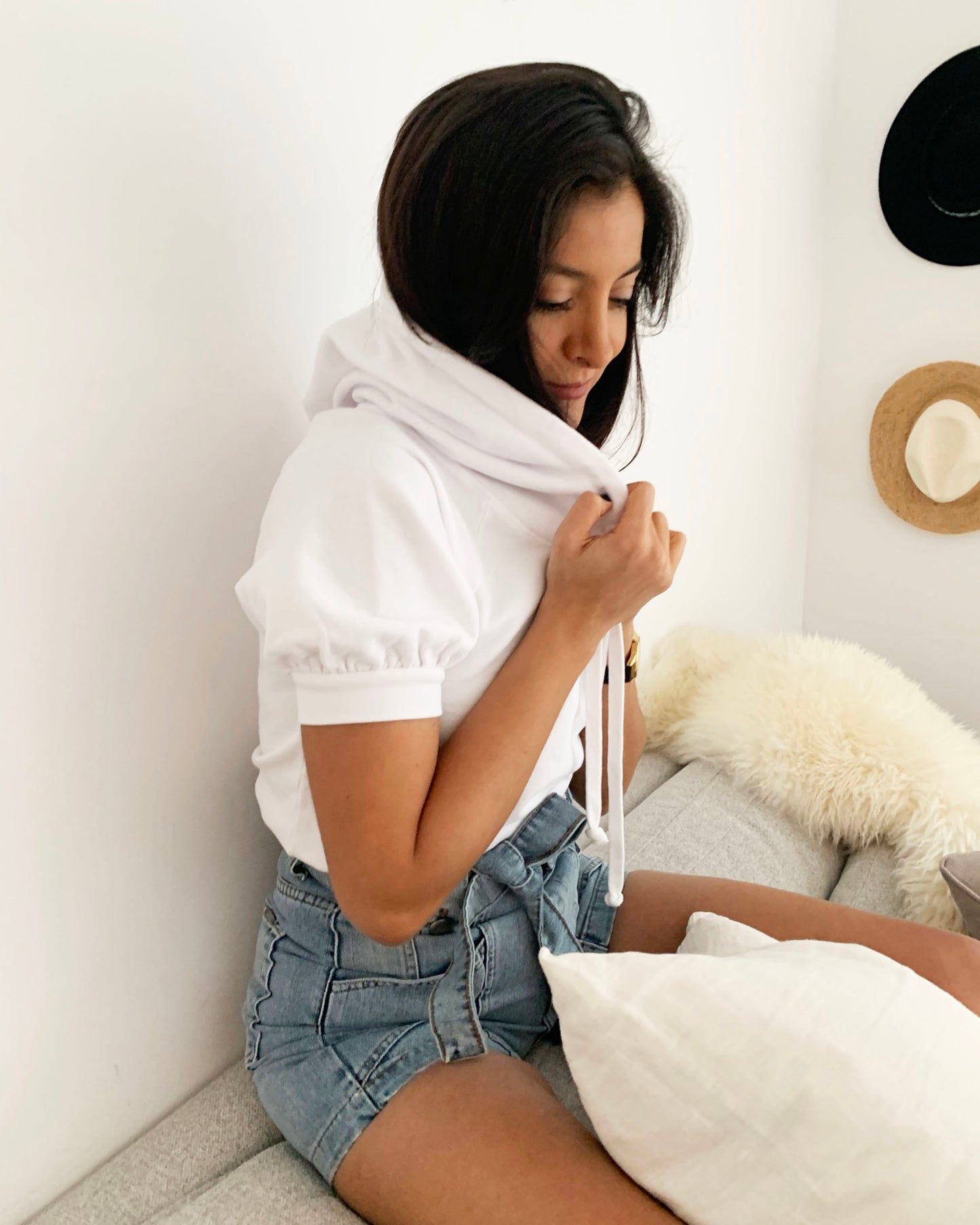 Side profile of white cotton short sleeve sweatshirt on model sitting on couch