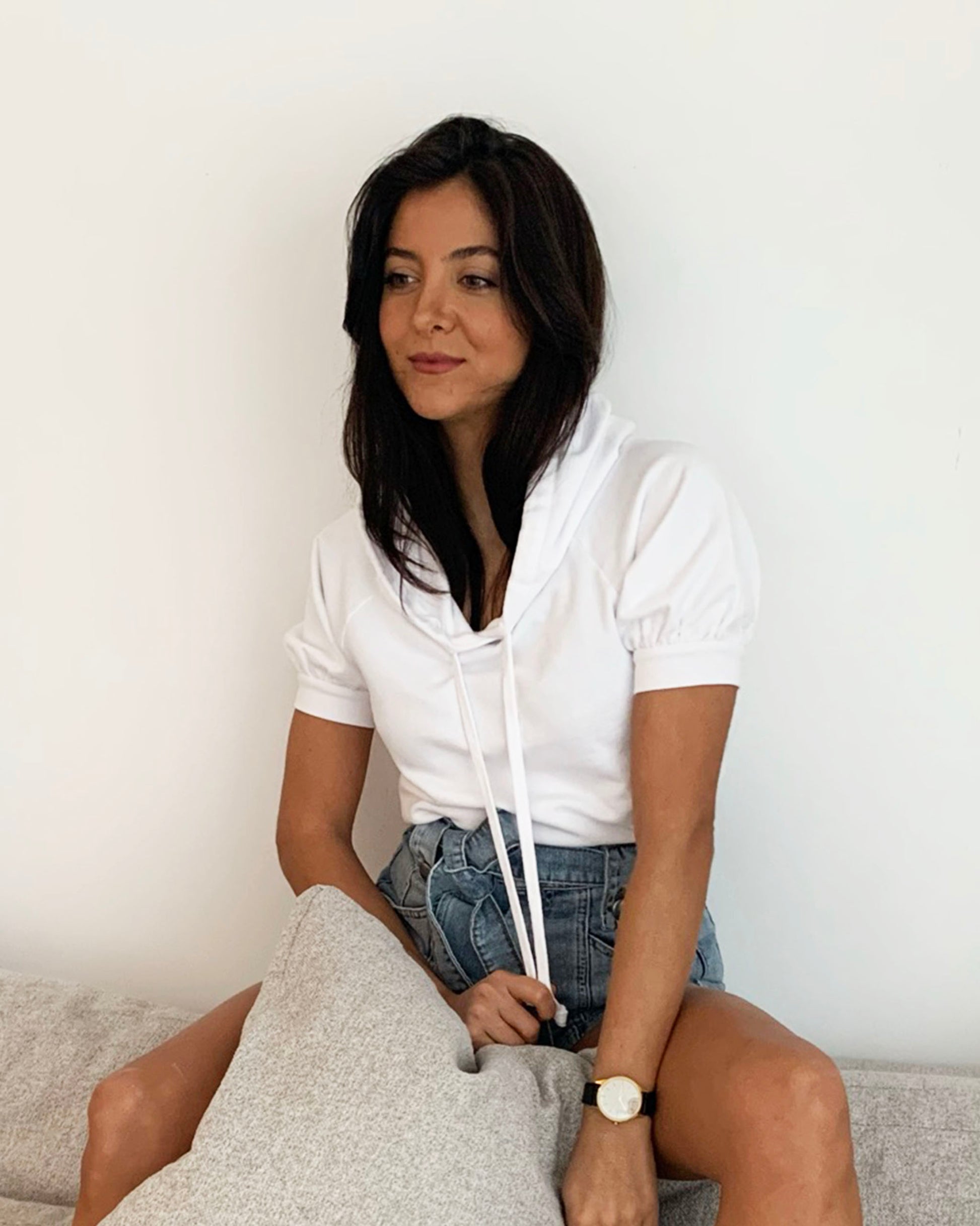 White cotton short sleeve sweatshirt on model sitting on couch in jean shorts