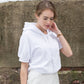 Side profile of White organic cotton short sleeve sweatshirt and cream silk skirt on brunette model looking down and holding neck