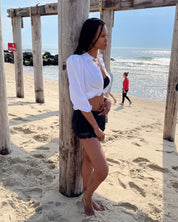Side profile of model wearing white cotton puff sleeve button down with black shorts