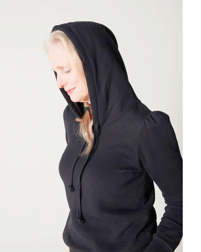 Side profile of black cotton fleece long sleeve sweatshirt on model with hood on