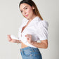 Side profile of model holding ties of white cotton puff sleeve wrap top 