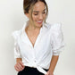 Tied white cotton puff sleeve button down on smiling model looking to side and holding knot