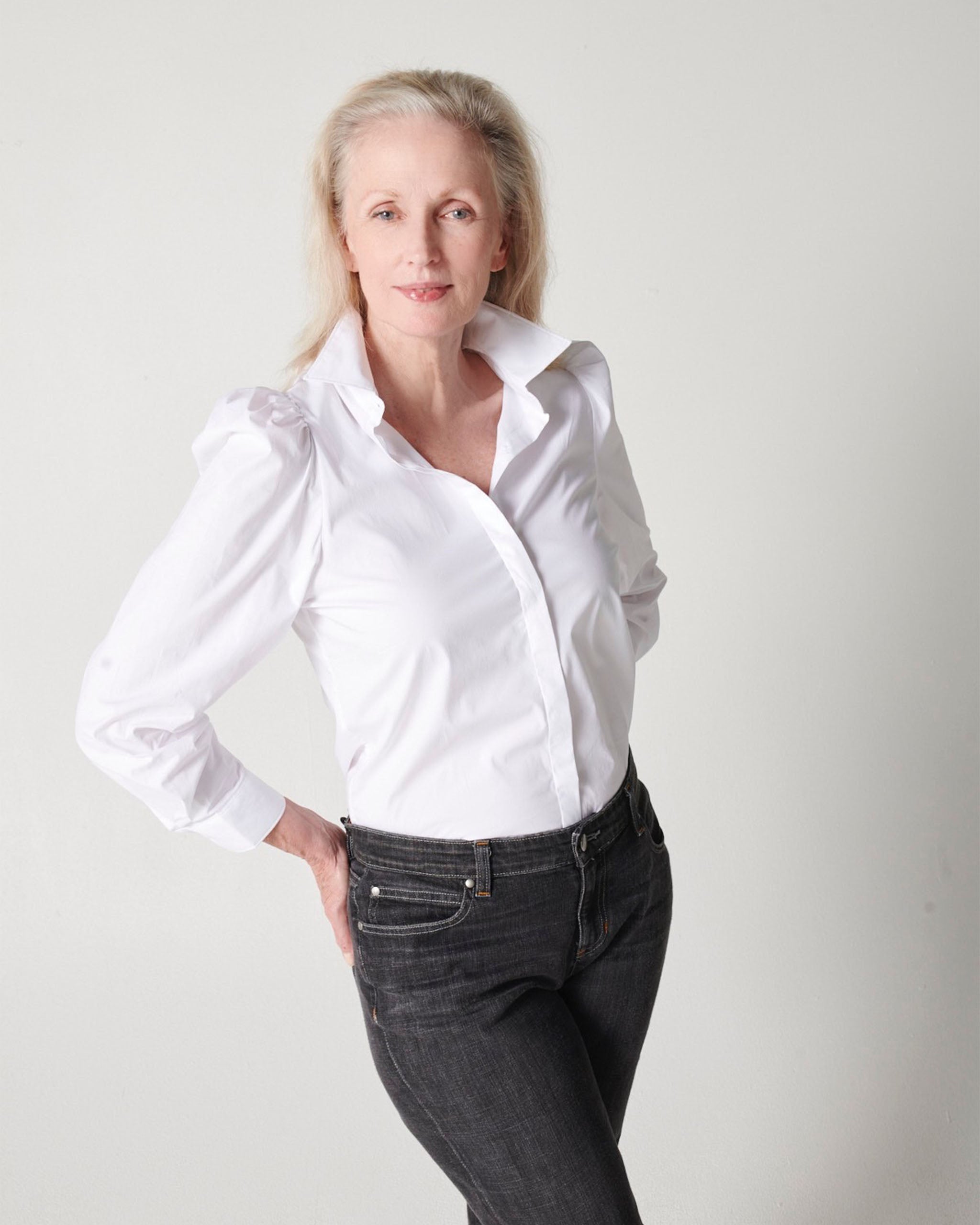 White cotton puff sleeve button down on older model wearing black jeans with hands in back pockets