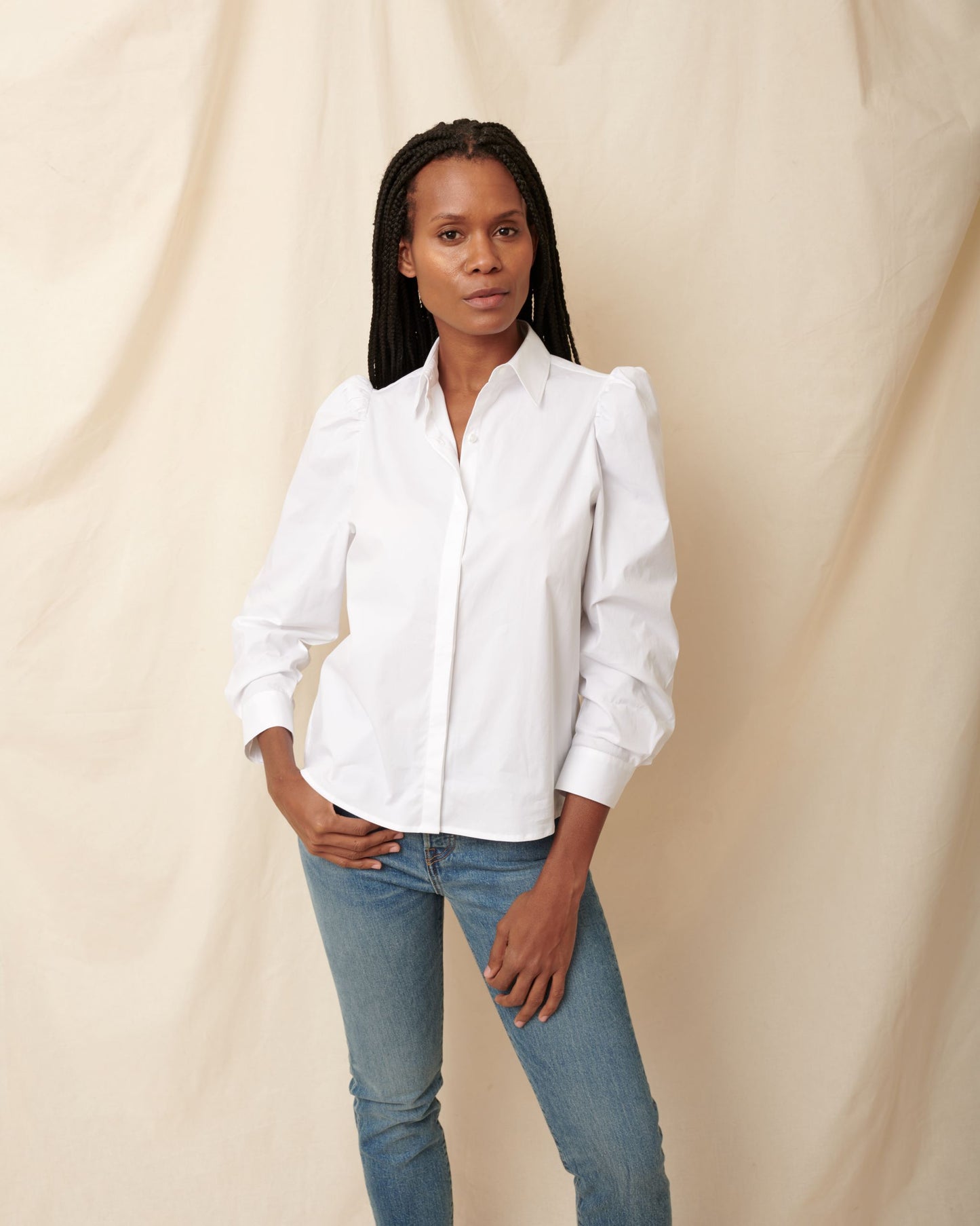 Black, fuller bust model pairing white cotton puff sleeve button down with blue jeans
