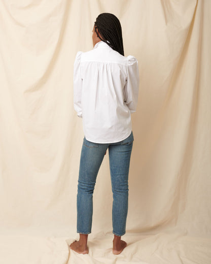Back detail of white cotton puff sleeve button down on model wearing blue jeans