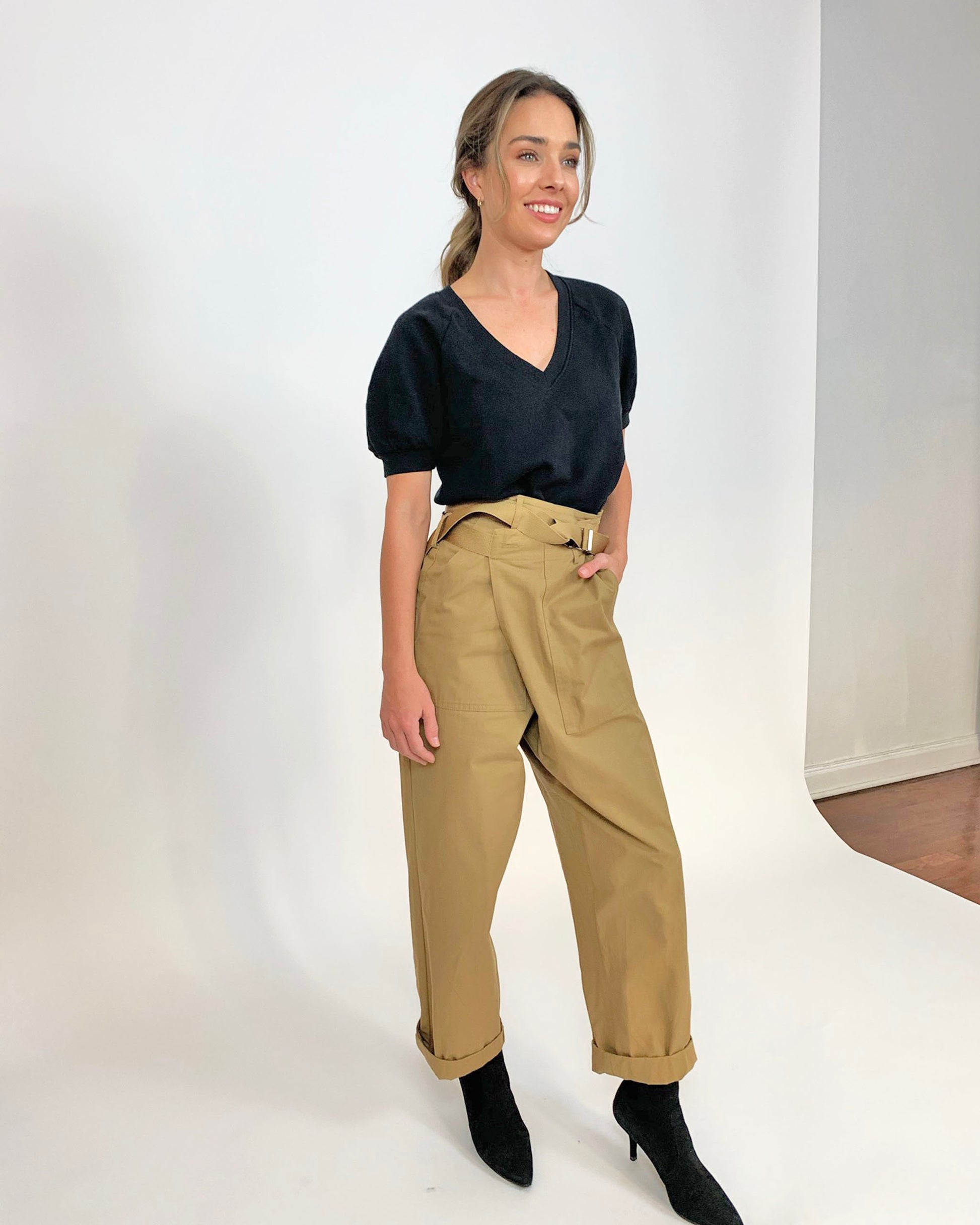 Black organic cotton v-neck sweatshirt on model in tan cargo pants and black heels with hand in pocket