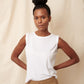 Thin, large chested black model wearing white pima cotton muscle tee with hands behind her back 