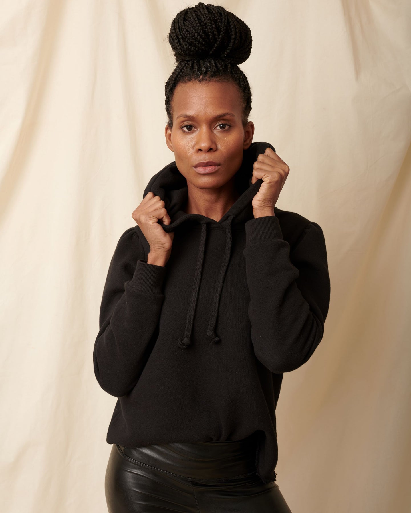 Black cotton fleece long sleeve sweatshirt on model holding hood