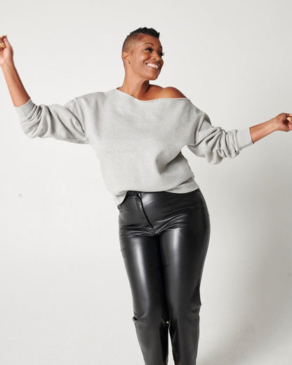 Dancing model wearing heather grey cotton fleece off-the-shoulder sweatshirt and black leather pants