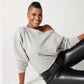 Heather grey cotton fleece off-the-shoulder sweatshirt on model sitting down in black leather pants