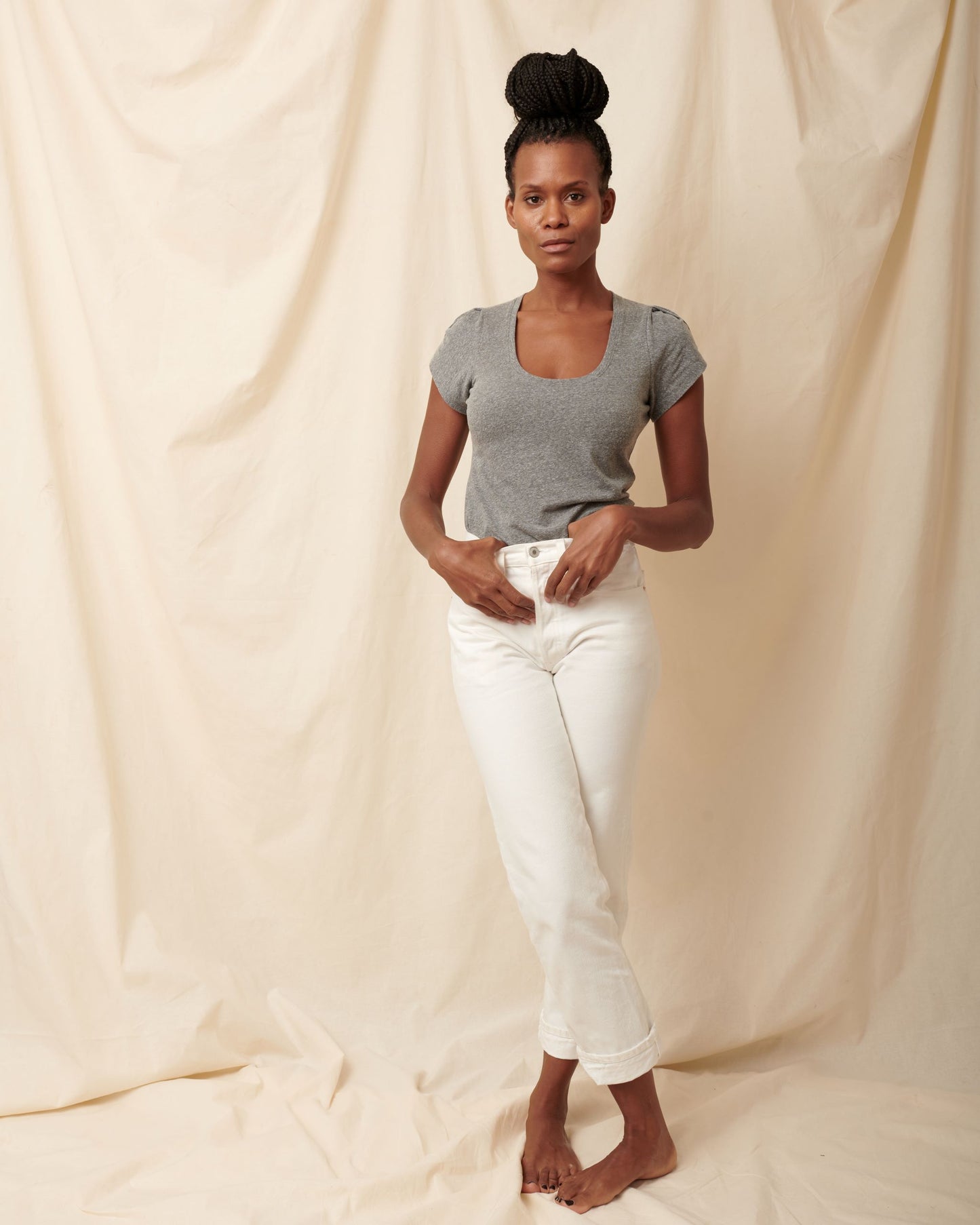 Heather grey supima cotton scoopneck tulip sleeve tee on black model wearing white jeans with hands on pockets
