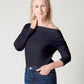Dark navy supima cotton off-the-shoulder tshirt on older, white model with hand on neck and other in pocket wearing blue jeans