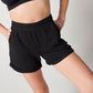 Black organic cotton sweat shorts and black bra on woman's body with hands on hips