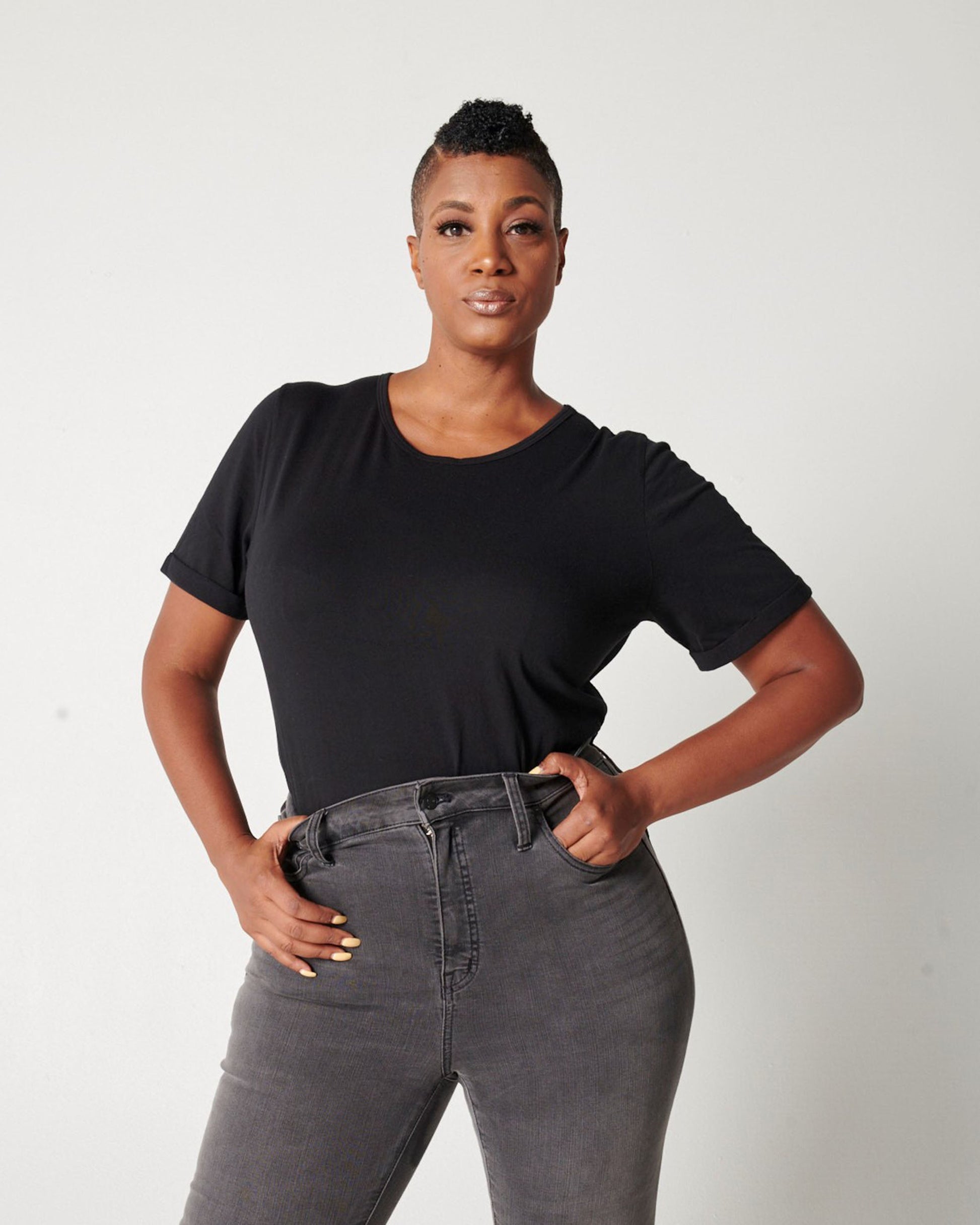 Black cotton crewneck, rolled sleeve tshirt on black fuller bust model wearing black jeans and hands in pockets