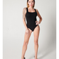 Black tank bodysuit on white model in blue polka-dot heels with hand on hip