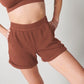 Vintage tobacco organic cotton sweat shorts and vintage tobacco bra on woman's body with hands on hips