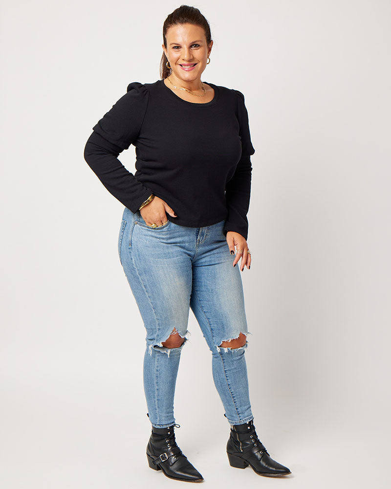 Black organic cotton double sleeve crewneck sweatshirt on model wearing ripped blue jeans and black boots with hand in pocket