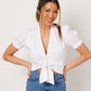 White cotton puff sleeve wrap top on smiling asian model wearing blue jeans with hands on hips