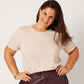 Close-up of latte cotton rolled sleeve tshirt tucked into plum leather pants on brunette model with hands on hips
