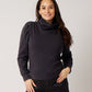 Black organic cotton turtleneck on smiling pregnant model in black silk pants holding belly