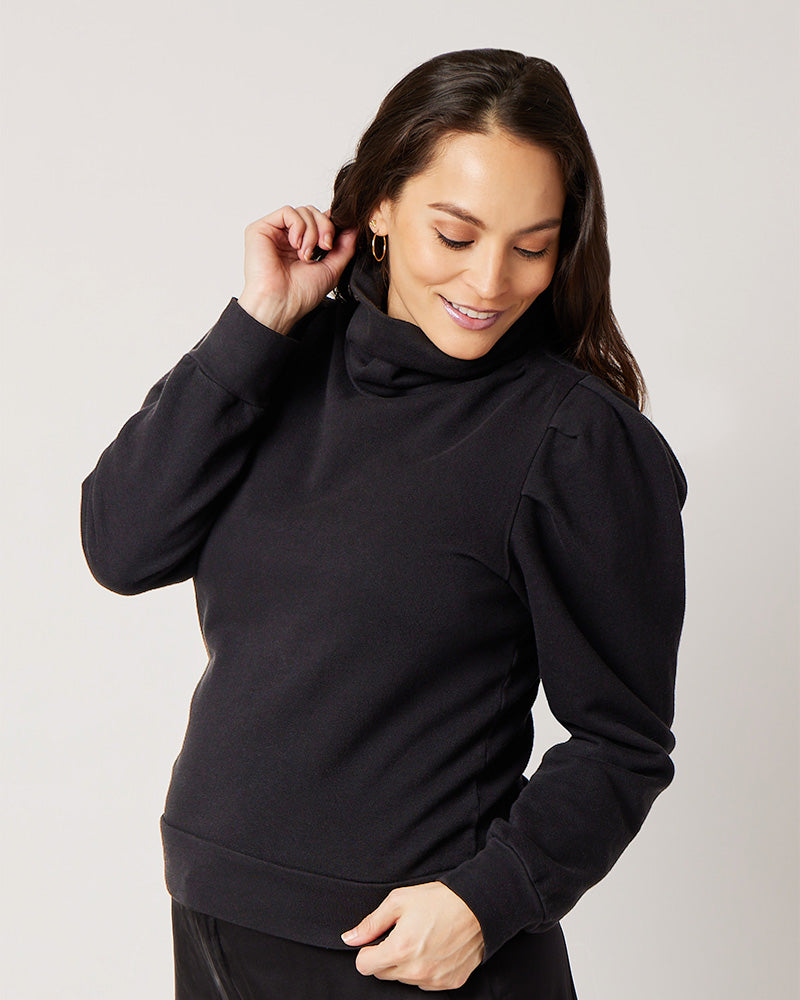 Side profile of black organic cotton turtleneck on pregnant model looking down while holding hair