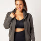 Grey cotton fleece puff sleeve zip up sweatshirt unzipped on model wearing black recycled polyester sports bra, black leggings, ponytail and gold hoops