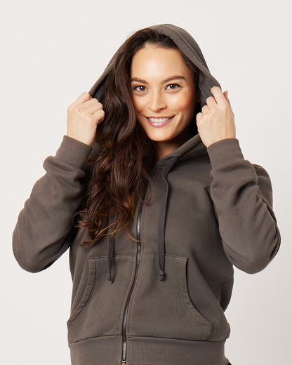 Grey cotton fleece puff sleeve zip up sweatshirt fully zipped on smiling pregnant model while putting on hood