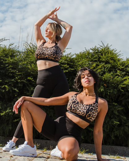 Leopard recycled polyester sports bra on 2 fuller bust models wearing white sneakers and black leggings in front of bush
