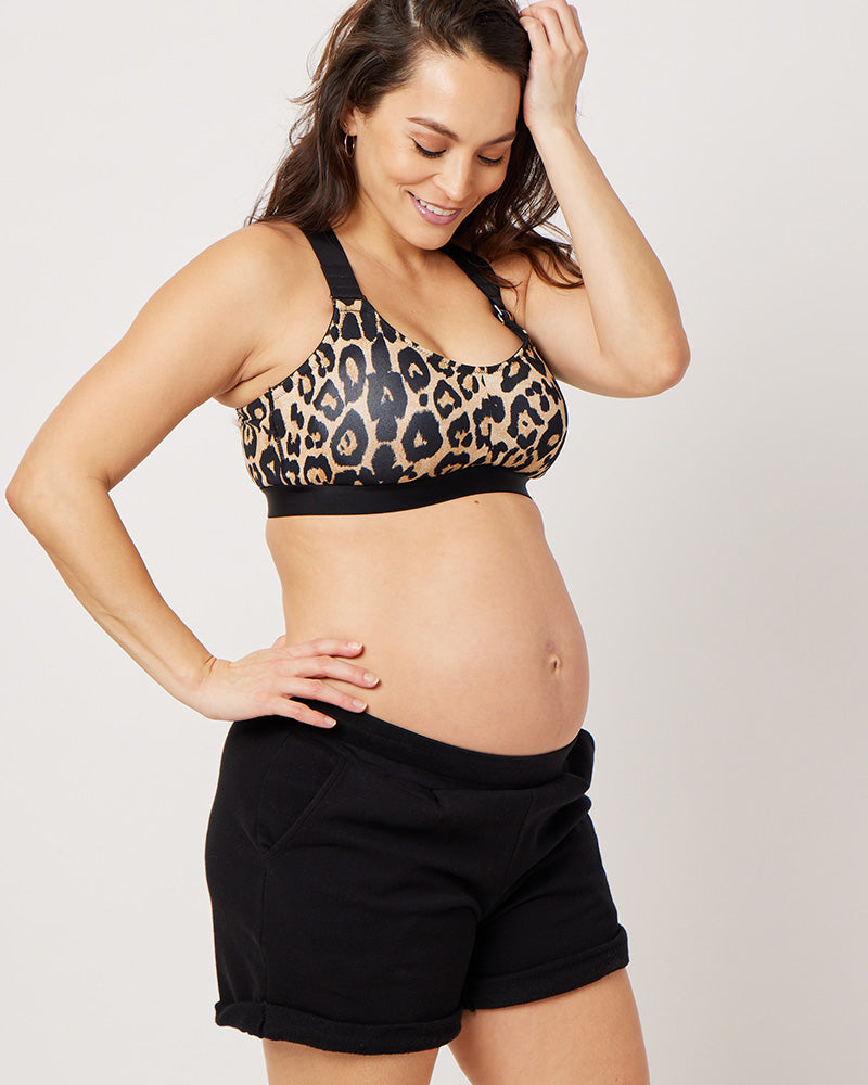 Leopard recycled polyester sports bra on pregnant model wearing black cotton sweat shorts and looking down