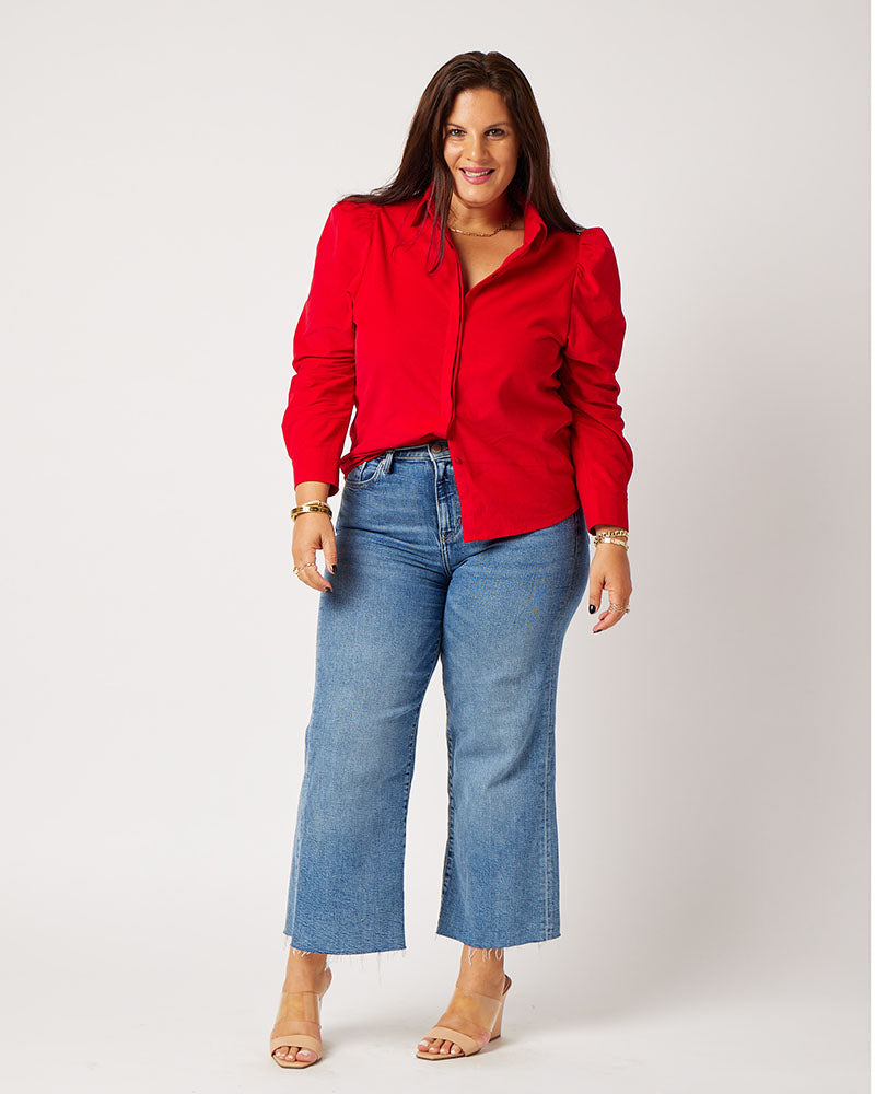 Red Japanese corduroy puff sleeve button down french tucked on smiling model wearing blue jeans and nude heels