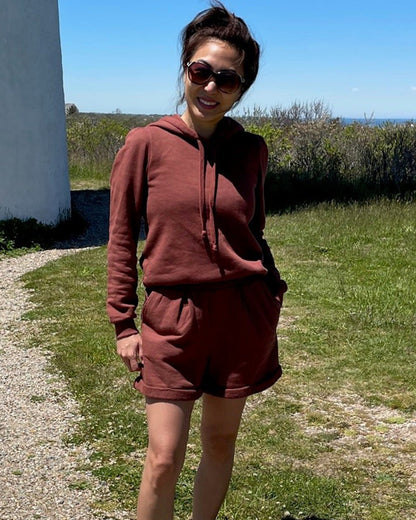 Vintage tobacco cotton fleece long sleeve sweatshirt and matching organic cotton pleated sweat shorts on smiling asian model in sunglasses on beach