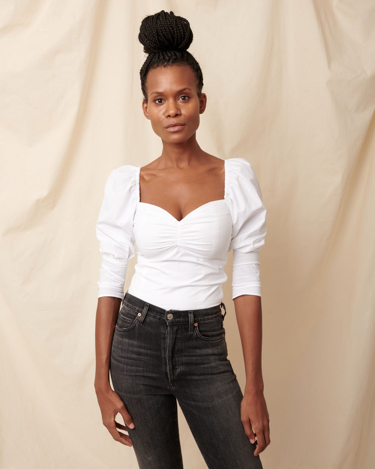 White cotton top with sweetheart neckline on black model wearing black jeans and hair in bun